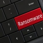 Imagem de um teclado de computador preto com uma tecla vermelha escrita ransomware