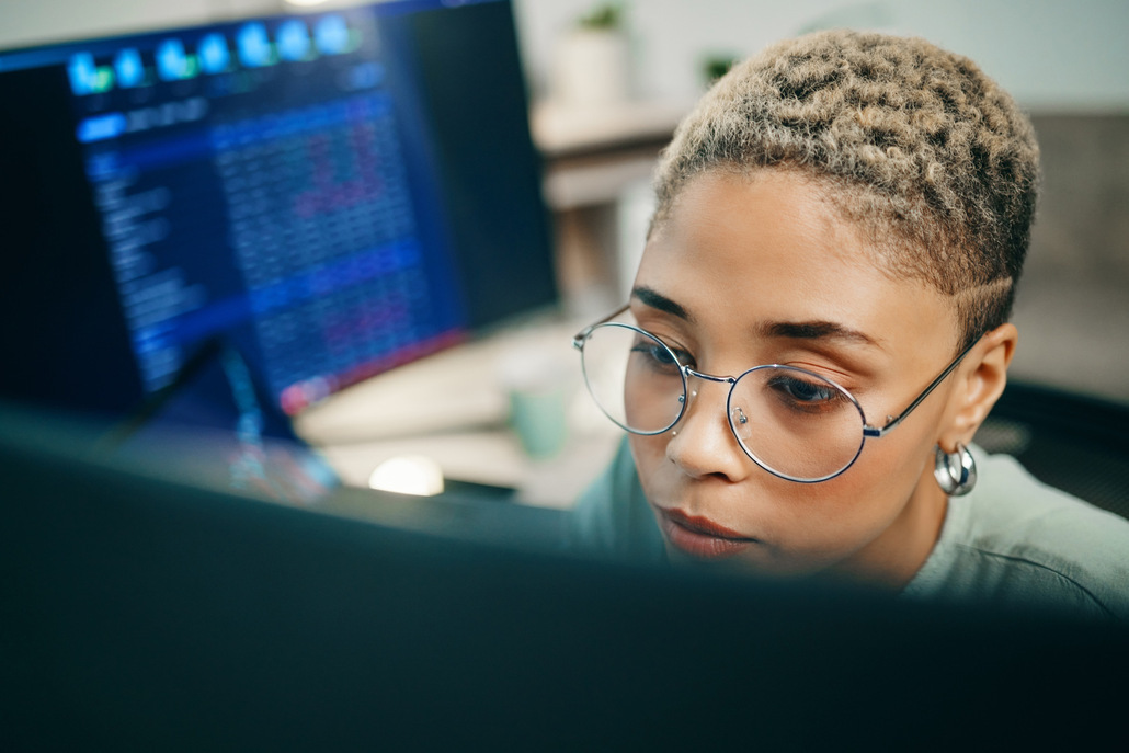 Mulher sentada diante do computador trabalha com um ERP.