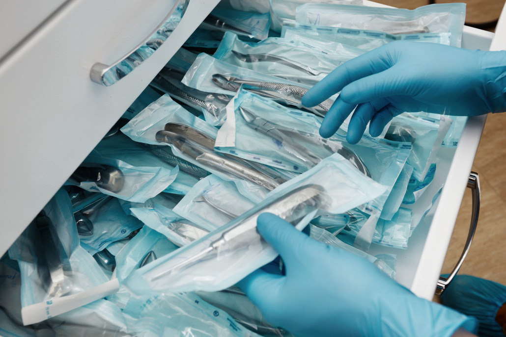 Uma mão com luvas conferindo o estoque de materiais odontologicos