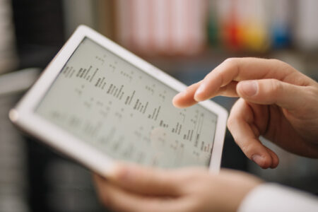 uma mão mexendo em um tablet com um checklist de régua de cobrança